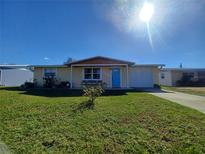 Cute ranch home with a well-manicured lawn and blue front door at 3818 Beechwood Dr, Holiday, FL 34691