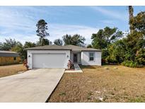 Newly constructed home with a white exterior, two-car garage, and landscaped yard at 5193 Deltona Blvd, Spring Hill, FL 34606