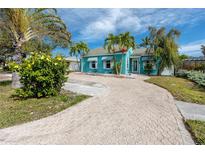 Beautiful teal home with palm trees and a brick driveway at 815 Lantana Ave, Clearwater Beach, FL 33767