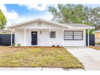 Charming white brick home with black accents and a well-manicured lawn at 8407 N Orangeview Ave, Tampa, FL 33617