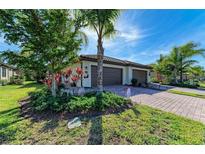 Two-car garage, landscaped yard, and paver driveway of this beautiful home at 12115 Amica Loop, Venice, FL 34293