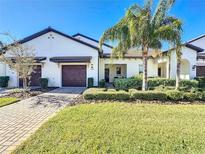Two-story home with dark brown double garage doors and landscaped lawn at 16847 Whisper Elm St, Wimauma, FL 33598