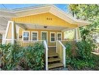 Charming yellow house with a front porch and lush landscaping at 809 E Lambright St, Tampa, FL 33604