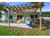 Inviting home exterior featuring a pergola, landscaping, and a blue chair at 8390 64Th N St, Pinellas Park, FL 33781