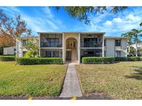 Front view of condo building with manicured lawn and walkway at 1400 Pine Glen Ln # B2, Tarpon Springs, FL 34688