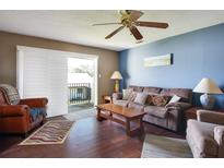 Cozy living room features wood floors, a brown couch, and sliding glass doors leading to a balcony at 4215 E Bay Dr # 1704C, Clearwater, FL 33764