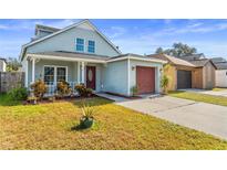 Charming light blue house with a red garage door and well-manicured lawn at 2432 Sagemont Dr, Brandon, FL 33511