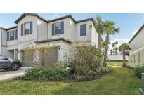 Two-story townhome with gray siding, two-car garage, and landscaped front yard at 36522 Well Hill Way, Zephyrhills, FL 33541