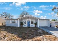 Gray house with blue door, brick facade, and a nicely landscaped yard at 4304 Woodfield Ave, Holiday, FL 34691