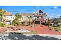 Charming two-story waterfront home with lush landscaping and a red-door entrance at 8050 Brighton Dr, Port Richey, FL 34668