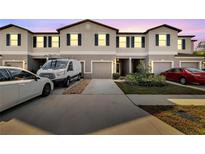 Townhouse exterior with driveway, landscaping, and two parked cars at 9655 Pembrooke Pines Dr, Sun City Center, FL 33573