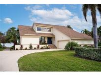 Two-story house with light-yellow walls, brown roof, and a landscaped lawn at 107 17Th St, Belleair Beach, FL 33786