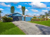 Blue house with driveway, garage, and landscaped lawn at 1409 Ne 49Th Ne Ave, St Petersburg, FL 33703