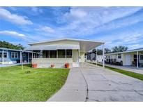 Nice yellow single-wide manufactured home with carport and landscaping at 4961 Britni Way, Zephyrhills, FL 33541