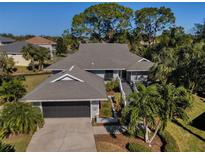 Attractive single-story home with gray roof, attached garage, and lush landscaping at 1012 Osprey Ct, Tarpon Springs, FL 34689