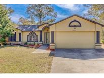 House exterior featuring a two-car garage and well-maintained lawn at 14140 Oakwood Dr, Hudson, FL 34669