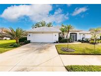 White house with a tile roof, landscaping, and a two-car garage at 728 Thistlelake Dr, Venice, FL 34293