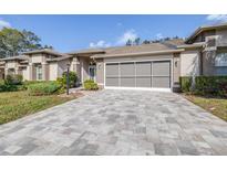 Tan two-story house with paver driveway and landscaping at 8041 Green Pines Ter, Spring Hill, FL 34606