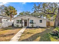 White bungalow with a walkway, landscaping, and mature trees at 1558 13Th S St, St Petersburg, FL 33705