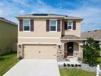 Charming two-story home with tan exterior, purple shutters, well-manicured lawn and inviting front entrance at 5808 Calla Lilly Dr, Sarasota, FL 34232