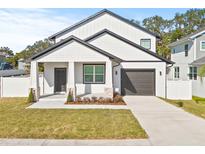 Charming white two-story home with a covered front porch and attached garage at 3006 E Columbus Dr, Tampa, FL 33605