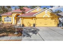 Yellow two-story home with a two-car garage and landscaped front yard at 16829 Midsummer Ln, Spring Hill, FL 34610