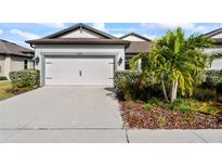 Front exterior of a single-story home with a two-car garage, driveway, and lush landscaping at 6421 Mooring Line Cir, Apollo Beach, FL 33572