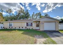 Single-story home with attached garage and landscaped front yard at 5624 Mccoy Ct, Zephyrhills, FL 33542