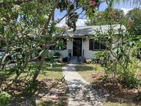 Charming home with a well-manicured lawn and inviting walkway through lush trees and flowers at 1529 Paloma Ln, Dunedin, FL 34698
