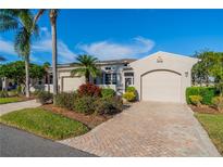 Exterior view of charming villa with landscaped grounds and two-car garage at 2463 Kensington Greens Dr, Sun City Center, FL 33573