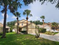 Charming two-story home featuring a well-manicured lawn, attached garage, and beautiful palm tree landscaping at 11908 Whisper Creek Dr, Riverview, FL 33569