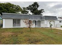 Charming single-Gathering home with a gray tiled roof, white exterior, and attached garage at 3349 Overland Dr, Holiday, FL 34691