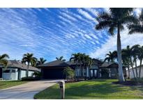 Beautiful home with a landscaped lawn, palm trees, and a two-car garage at 8384 Antwerp Cir, Port Charlotte, FL 33981