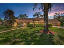 Charming single story home with a well-manicured lawn, mature trees, and cozy front porch at 1055 Riverside Ridge Rd, Tarpon Springs, FL 34688