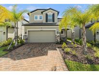 Charming two-story home with a brick driveway, gray siding, and well-manicured landscaping at 37868 Beacon Brick Dr, Zephyrhills, FL 33540