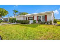 White single story home with red accents, well-manicured lawn, and palm trees at 9125 41St N St, Pinellas Park, FL 33782