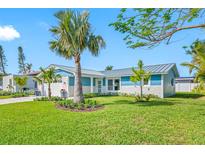 Charming blue and white home featuring a well-manicured lawn, lush landscaping, and a two-car garage at 819 59Th Ave, St Pete Beach, FL 33706