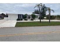 Newly renovated home with a modern exterior, featuring a lush lawn and driveway at 87 Rotonda Cir, Rotonda West, FL 33947