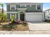 Two-story house with green exterior, landscaping, and a two-car garage at 11351 Callaway Pond Dr, Riverview, FL 33579