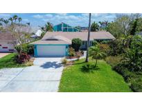 Charming single-Gathering home features lush landscaping, bright turquoise exterior, and a two-car garage at 2993 W Vina Del Mar Blvd, St Pete Beach, FL 33706