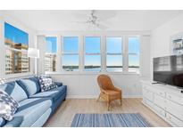Comfortable living room with waterfront views, blue couch, wicker chair, and TV at 5130 Brittany S Dr # 505, St Petersburg, FL 33715