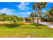 Charming single-story home with a lush green lawn and palm trees at 5416 Isabella Ave, Sarasota, FL 34235