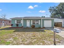 Newly renovated teal house with a one car garage and well-manicured lawn at 8422 Paxton Dr, Port Richey, FL 34668