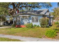 Charming light blue bungalow home with front porch and green lawn at 323 W Hanna Ave, Tampa, FL 33604