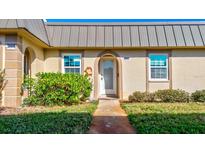 Front view of charming condo with metal roof and well-manicured landscaping at 4235 Stratford Dr, New Port Richey, FL 34652