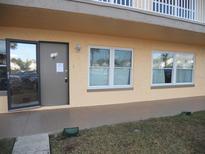 Front exterior of the condo unit with a glass storm door, windows, and a small patch of grass at 6400 46Th N Ave # 105, Kenneth City, FL 33709