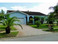 Light blue house with a large yard, palm trees, and a paved driveway at 1713 Grand Central Dr, Tarpon Springs, FL 34689