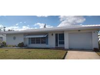 Charming single-story home featuring an attached garage, blue awning, and well-manicured lawn at 9350 Mainlands W Blvd, Pinellas Park, FL 33782