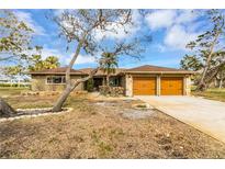 Front exterior of a single-story home with a two-car garage and landscaping at 945 Bayshore Dr, Tarpon Springs, FL 34689