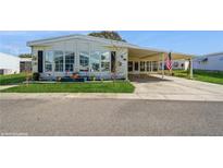 White single-wide manufactured home with carport, landscaping, and American flag at 233 Tarpon Ln, Oldsmar, FL 34677